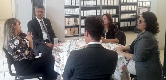 Foto mostra três mulheres e três homens de pé, conversando.