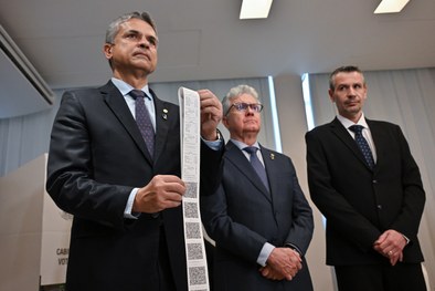 Coordenadora de acessibilidade auxilia um eleitor com deficiência visual