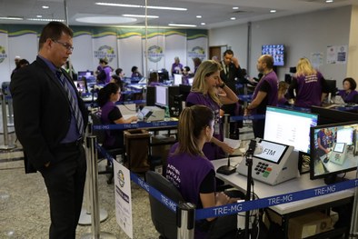 Coordenadora de acessibilidade auxilia um eleitor com deficiência visual