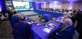 Foto mostra presidentes dos TREs sentados ao redor de uma mesa em formato de U. Ao fundo, um hom...
