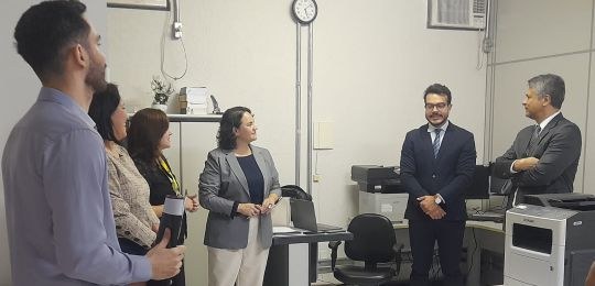 Foto mostra três mulheres e três homens de pé, conversando.