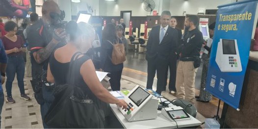 Eleitora é filmada por jornalista enquanto treina o voto na urna eletrônica com simulador.
