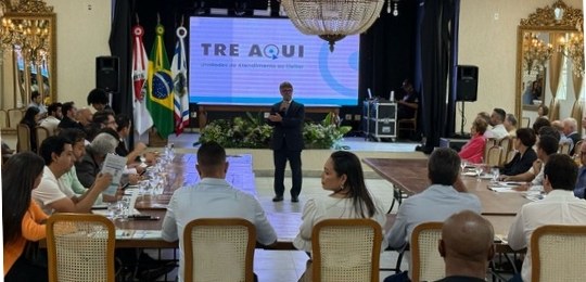 Juiz Carlos Donizetti, de pé, fala para pessoas sentadas ao redor de uma mesa.