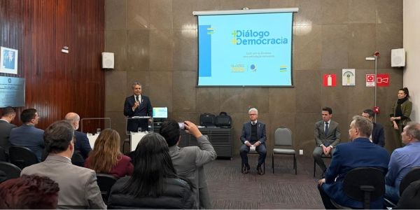 Foto mostra o desembargador Carlos Henrique Perpétuo Braga de pé, no canto esquerdo. Em primeiro...