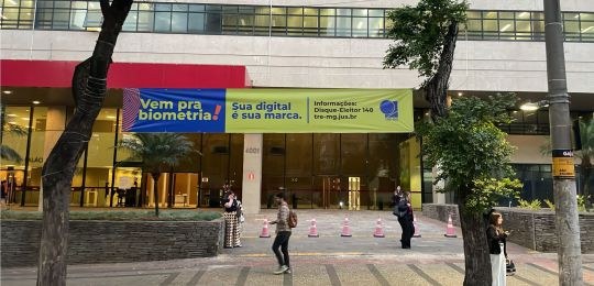 Foto mostra uma faixa na fachada de um prédio do TJMG A faixa tem os dizeres "Vem pra biometria!...