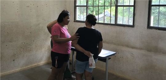 Foto mostra três mulheres junto a uma urna eletrônica.
