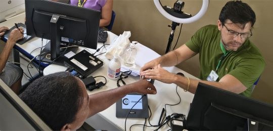 Servidor Bruno Mattos colhe as digitais de uma eleitora