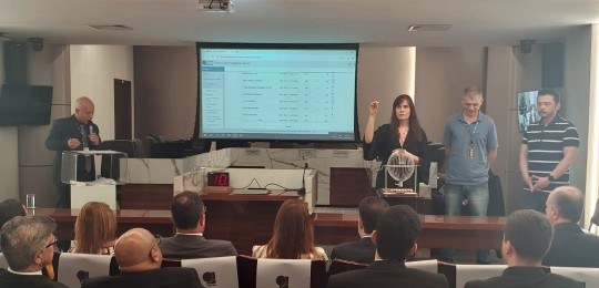 Audiência horário eleitoral gratuito BH 2024 Em primeiro plano, pessoas sentadas de costas para a câmera. Ao fundo, uma mulher branca de cabe...