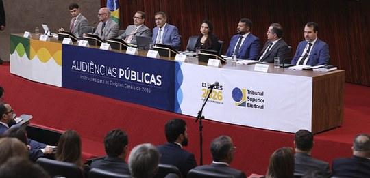Audiência pública no plenário do TSE. No palco, há uma mesa longa com o ministro Nunes Marques e...