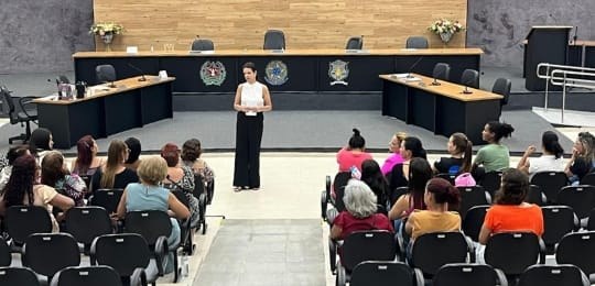 Foto mostra a servidora TRE-MG Cláudia Sapi de pé, durante conversa com mulheres que estão senta...