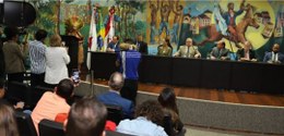 Foto da cacica Ãgohó durante discurso. Ela está de pé no canto esquerdo, vestindo saia de palha ...