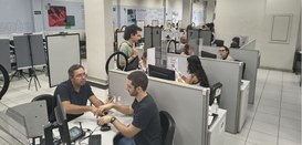 Foto mostra eleitores e servidores em guichês de atendimento na Central de Atendimento ao Eleito...