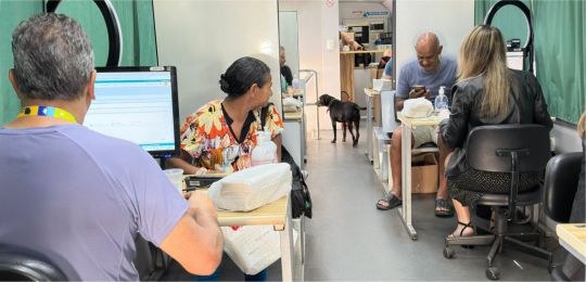 Foto mostra uma eleitora idosa e sua acompanhante durante atendimento no ônibus TRE Aqui.
