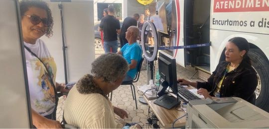 Foto mostra uma eleitora idosa e sua acompanhante durante atendimento no ônibus TRE Aqui.