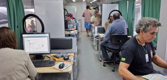 Foto mostra eleitores sendo atendidos por servidores do TRE-MG dentro de um ônibus.