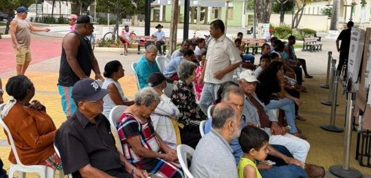 Foto mostra uma eleitora idosa e sua acompanhante durante atendimento no ônibus TRE Aqui.