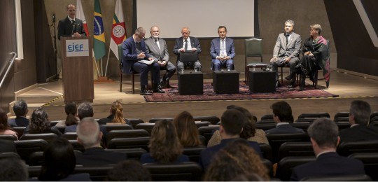 Desembargador Júlio César Lorens durante discurso. Ele está de pé, no canto esquerdo da foto. À ...