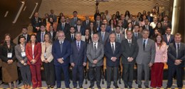 Foto mostra cerca de 60 pessoas de pé, dentro de um auditório, posando para a foto.
