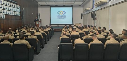 Ao fundo, des. Júlio César Lorens durante discurso. Em primeiro plano, policiais militares na pl...