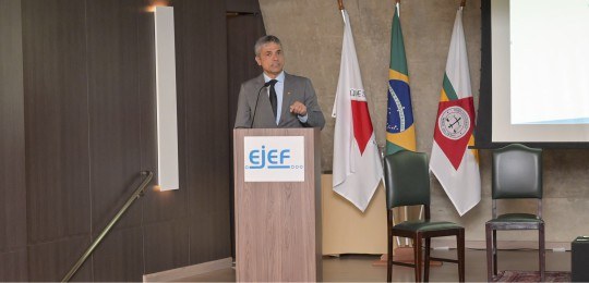 Desembargador Júlio César Lorens durante discurso. Ele está de pé, no canto esquerdo da foto. À ...