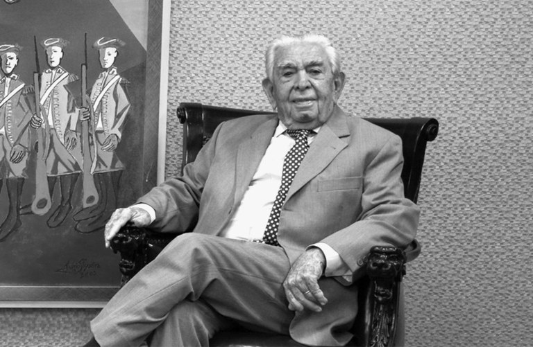 Foto em preto e branco do desembargador José Fernandes Filho. Ele veste terno e está sentado em ...