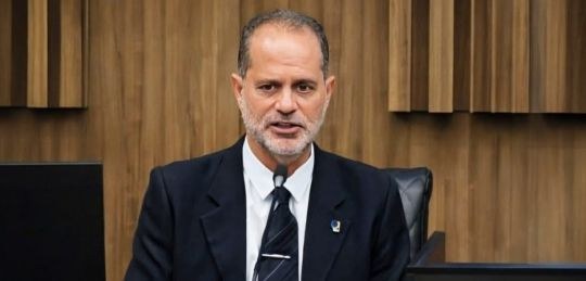 Desembargador Júlio César Lorens durante discurso. Ele veste paletó preto, camisa branca e grava...