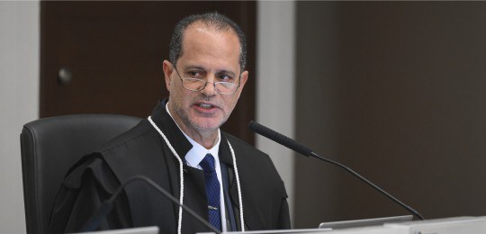 Foto do desembargador Júlio César Lorens falando ao microfone. Ele está de óculos.