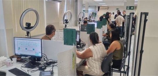 Foto mostra uma fila de pessoas junto ao ônibus com identidade visual TRE Aqui