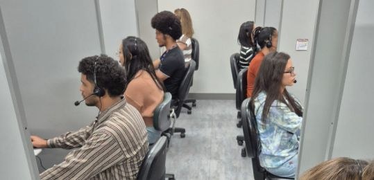Foto mostra uma fila de pessoas junto ao ônibus com identidade visual TRE Aqui