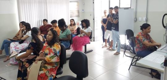 Foto mostra uma fila de pessoas junto ao ônibus com identidade visual TRE Aqui