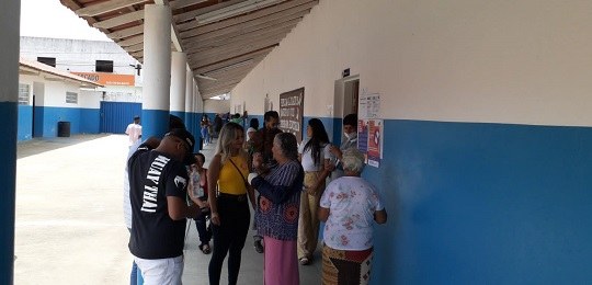 Foto mostra eleitores na entrada de uma escola estadual.