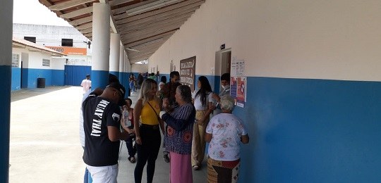 Foto mostra eleitores na entrada de uma escola estadual.