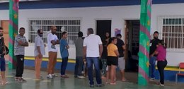 Foto mostra eleitoras e eleitores em fila na porta de uma seção eleitoral.