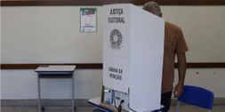 Foto de eleitor moreno, de cabelos grisalhos, na cabine de votação.