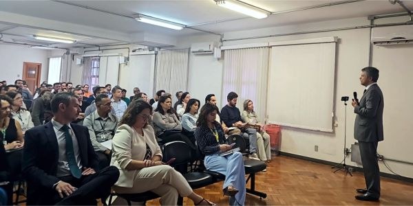 Desembargador Carlos Henrique Perpétuo Braga, de pé no canto direito, fala para dezenas de servi...