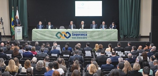 Encontro Nacional de Segurança nas Eleições Ministro Alexandre de Moraes de pé durante palestra. Em primeiro plano, pessoas sentadas na plat...
