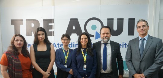Foto mostra a estação de atendimento ao eleitor. Duas mesas com alguns equipamentos de informáti...
