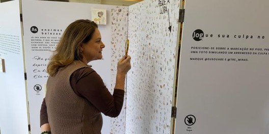 Foto mostra duas mulheres interagindo com elementos nos painéis de uma exposição.