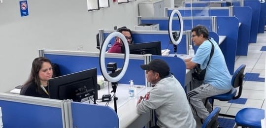 Foto mostra dois homens sendo atendidos por uma servidora e um servidor do TRE.