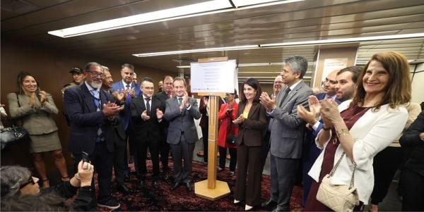 Foto mostra diversas autoridades ao redor de uma placa posicionada em um pedestal de madeira