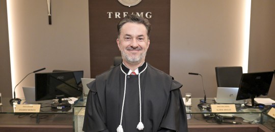 Foto do juiz Henrique Oswaldo Pinto Marinho. Ele veste uma toga preta e sorri para a câmera.