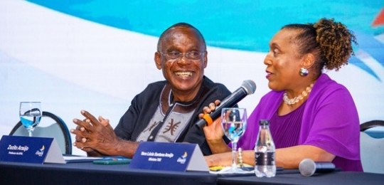 Fota mostra homens e mulheres sentados ao redor de uma grande mesa em formato de U.