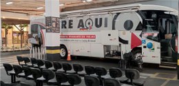 Foto mostra um ônibus com plotagem TRE Aqui, em um estacionamento coberto.
