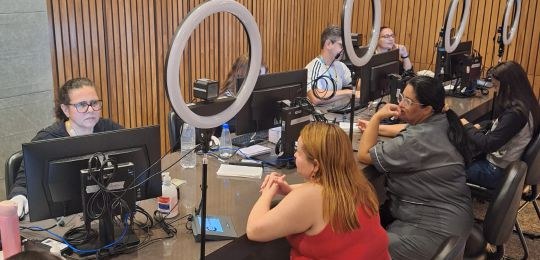 Foto mostra duas mulheres e uma adolescente sendo atendidas por servidores do TRE-MG.