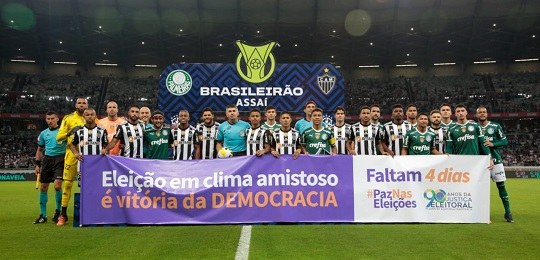 Jogadores de Atlético Mineiro e Palmeiras seguram uma faixa com os dizeres eleição em clima amis...