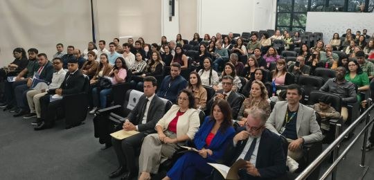 Foto mostra dezenas de pessoas de pessoas sentadas na plateia de um auditório