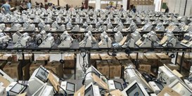 Foto mostra dezenas de urnas eletrônicas sobre bancadas, dentro de um galpão.