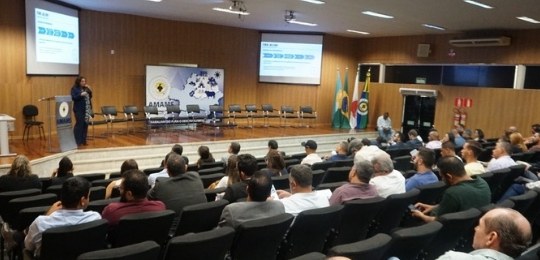 Diretora-geral do TRE-MG, Sandra Freire, discursa no canto esquerdo de um palco. A foto também m...