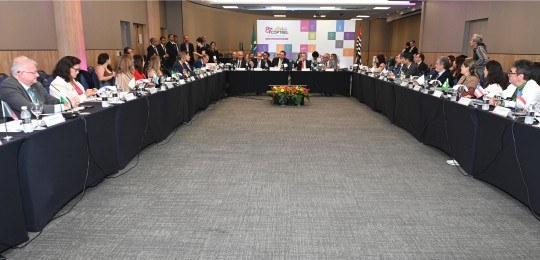 Presidentes dos TREs sentados ao redor de uma mesa em formato de U, durante reunião. Eles olham ...