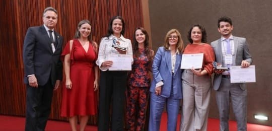 Cláudia Sapi (de blusa branca), Lara Ferreira (de blusa laranja) e Emerson Matos (terno cinza cl...